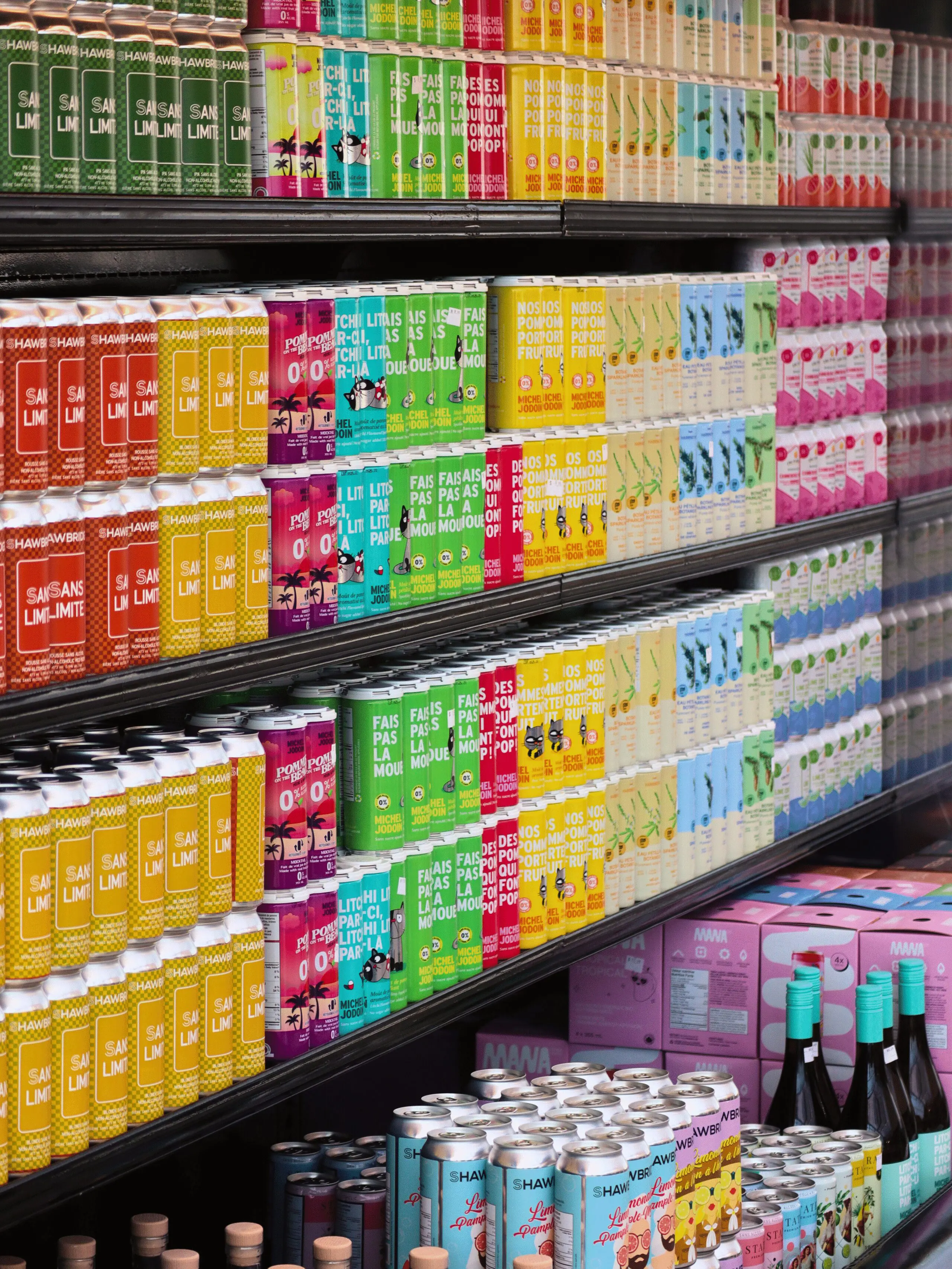 Un rayon d'épicerie rempli de rangées de boissons colorées en boîte et en canette, classées par saveur et par marque, créant un étalage vibrant et visuellement attrayant.