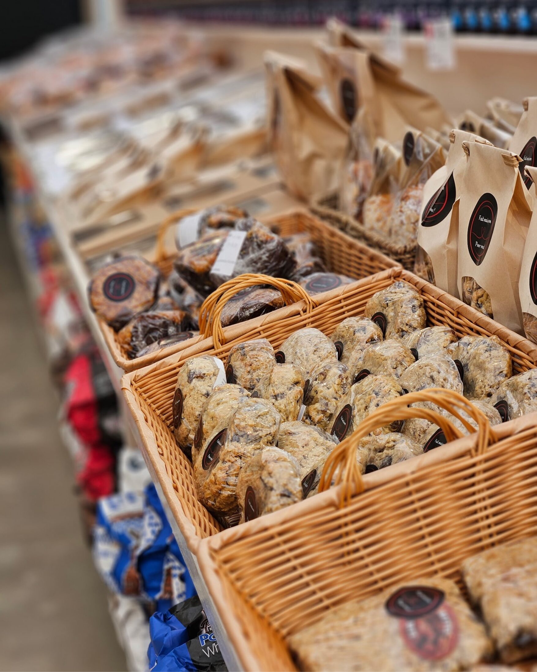 Des paniers en osier remplis de différents types de pains et de produits de boulangerie sont exposés sur le comptoir d'un magasin, les paquets et les pains étant soigneusement disposés en rangées.